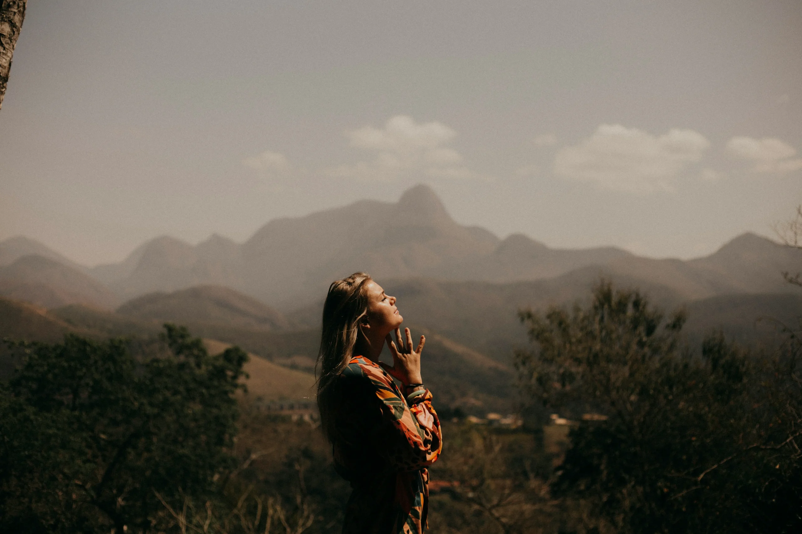 Woman standing peacefully in the Balkan mountains, enjoying nature with layered hills and soft light in the background